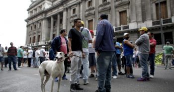 A supporter of greyhound racing stands with his dog outside Congress in Buenos Aires, Argentina, Wednesday, Nov. 16, 2016. Lawmakers are expected to vote Wednesday on a law that would prohibit greyhound racing in the country. (AP Photo/Victor R. Caivano)